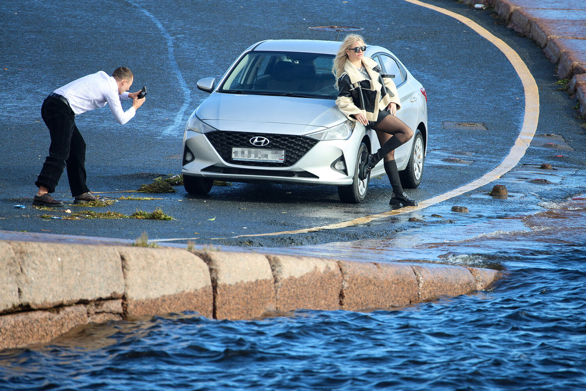 Парень фотографирует девушку у автомобиля на фоне Невы, 11 октября 2025 года ©Валентин Егоршин/ТАСС  📷