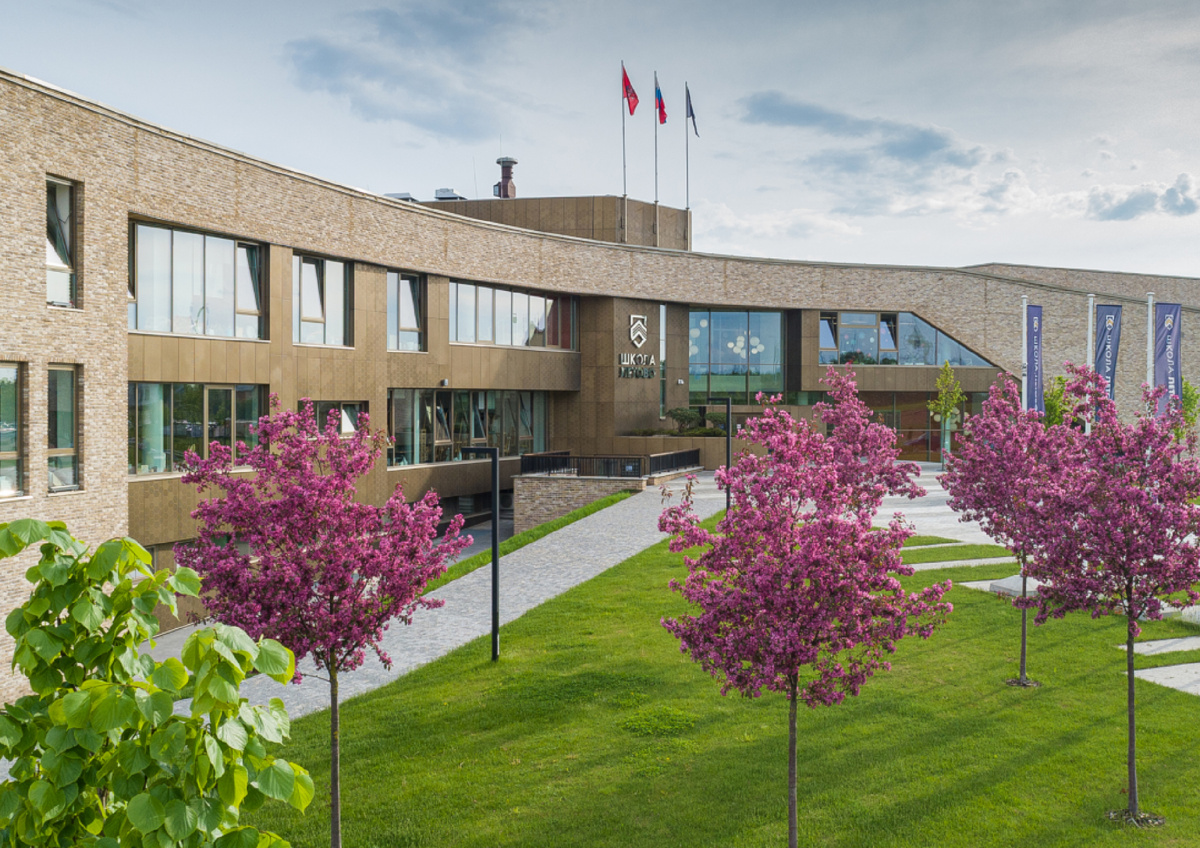 У входа в школу «Летово» ухоженный газон, деревья и лавочки, на которых дети могут дождаться начала занятий или отдохнуть после них