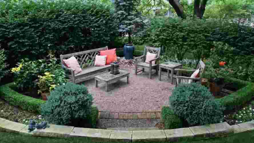 Садовая комната в форме угла. Стенаны комнаты из высоких растений, живых бордюров и подпорной стенки на первом плане.