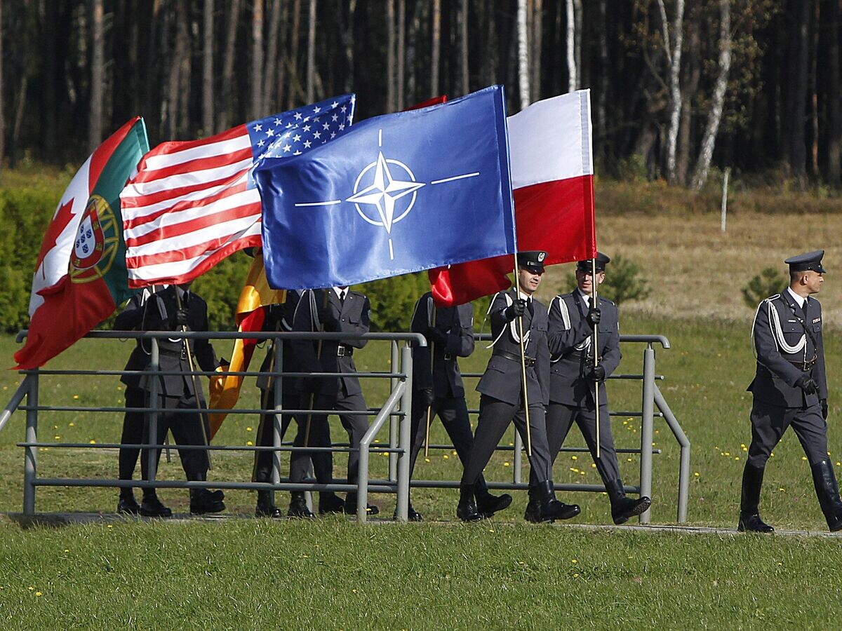    Военнослужащие с флагами США, НАТО и Польши на авиабазе в Ласке© AP Photo / Czarek Sokolowski