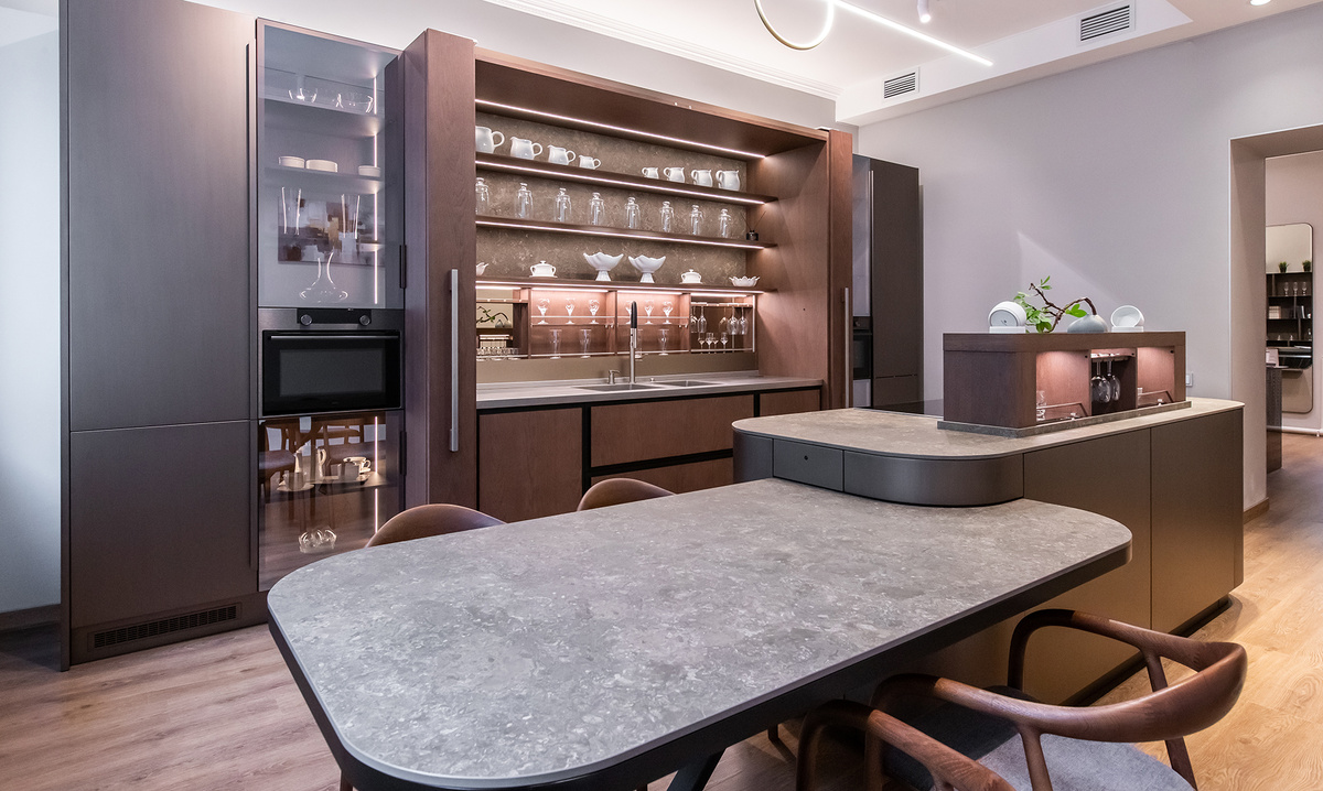 Благородная элегантность эмали под бронзу, теплота натурального шпона Дуб Vintage с индивидуальной тонировкой и таинственный блеск стекла Attico Bronze создают сложный и многогранный образ этого комплекта кухонной мебели.