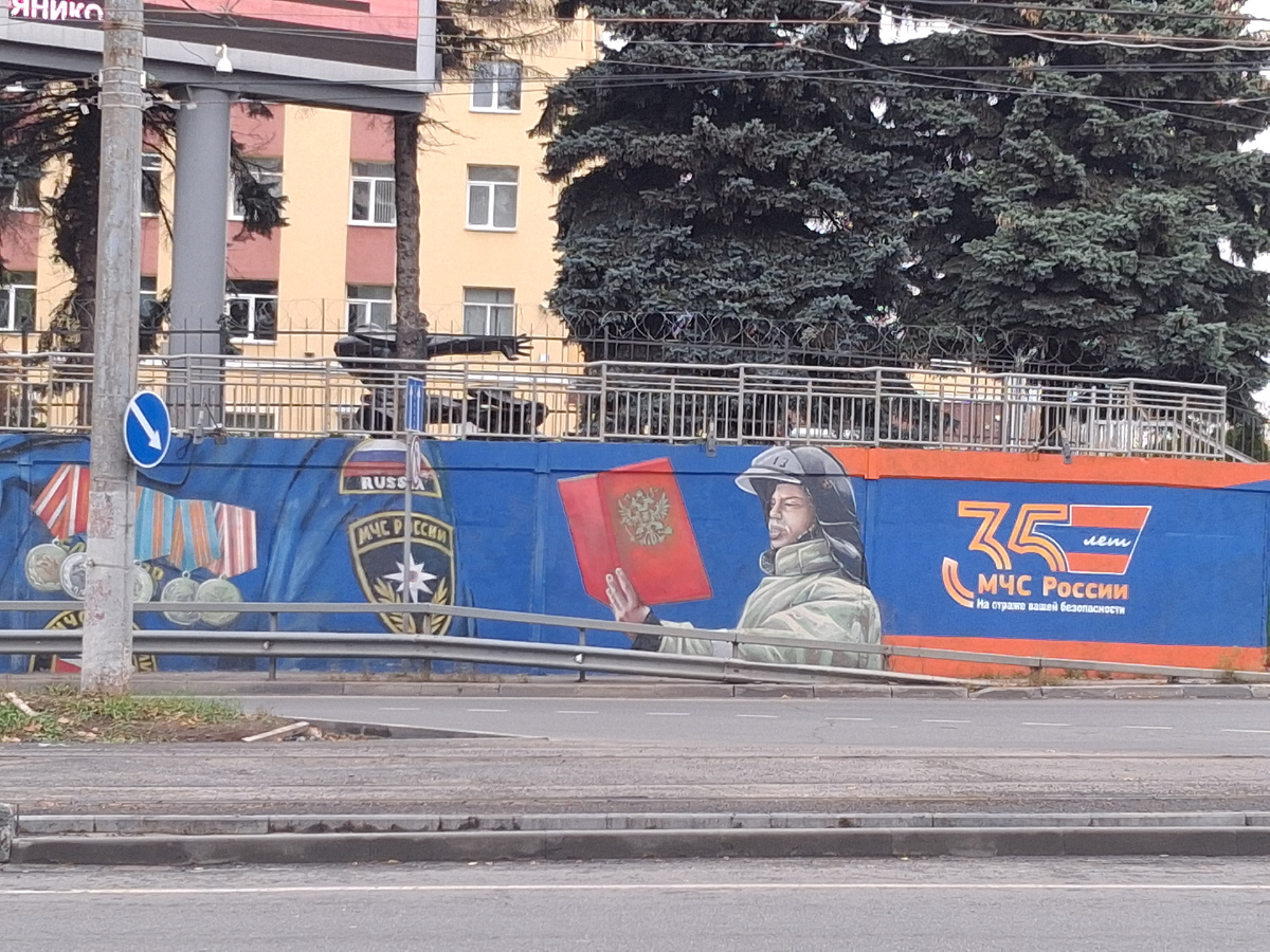 На мурале слева направо: медали, шеврон, клятва пожарного. На заднем плане - памятник пожарному. Фото автора.