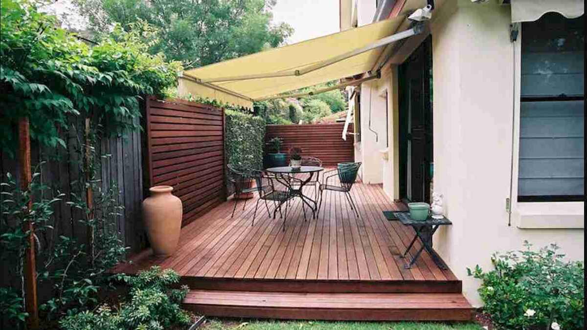 Зеленая комната в узком простhанстве. Забор декорирован деревянной панелью и искусственной лианой. 