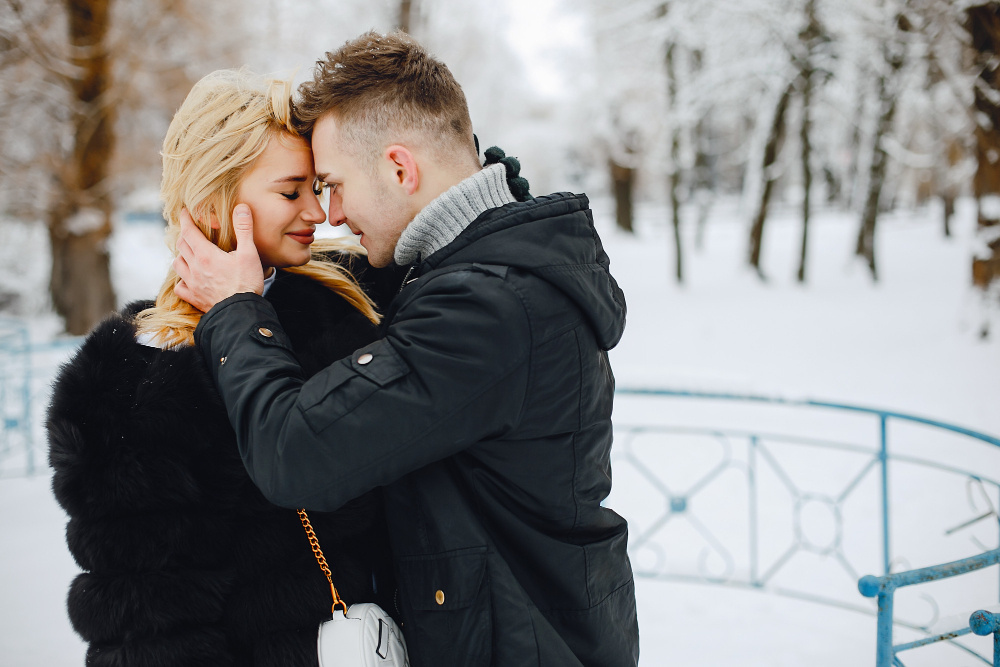 Влюблённая пара обнимается на зимней прогулке, символизируя тёплые чувства и начало любви