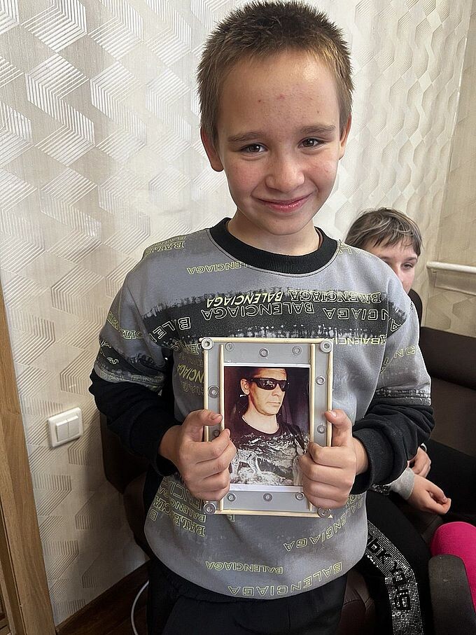 Мальчик держит в руках изготовленную им рамку с фотографией его отца