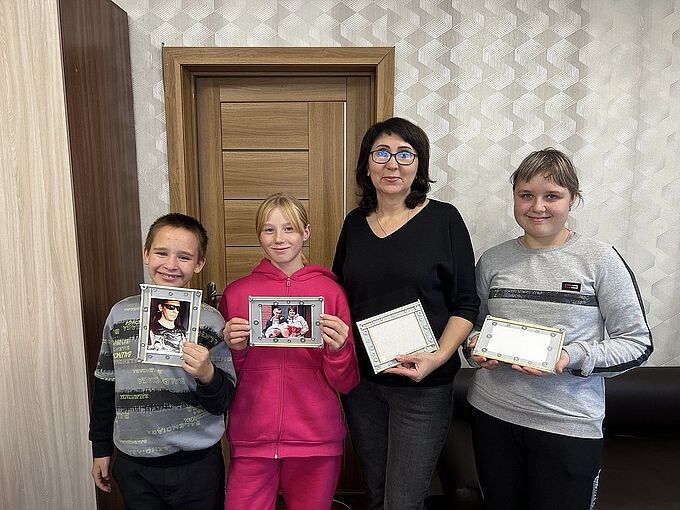 Дети и Заречнева Лариса Павловна показывают изготовленные ими рамки для фотографий