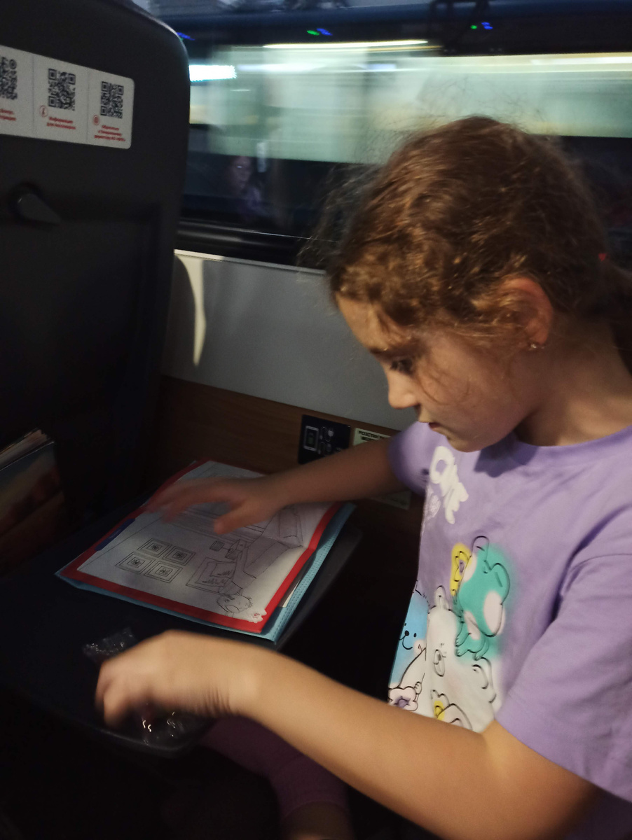 Раннее утро в поезде. Дочка изучает подарок от РЖД