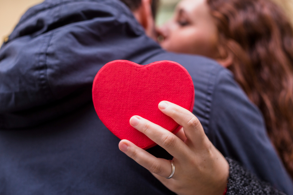 Женщина держит в руках красное сердце, символизируя любовь, привязанность и искренние чувства.