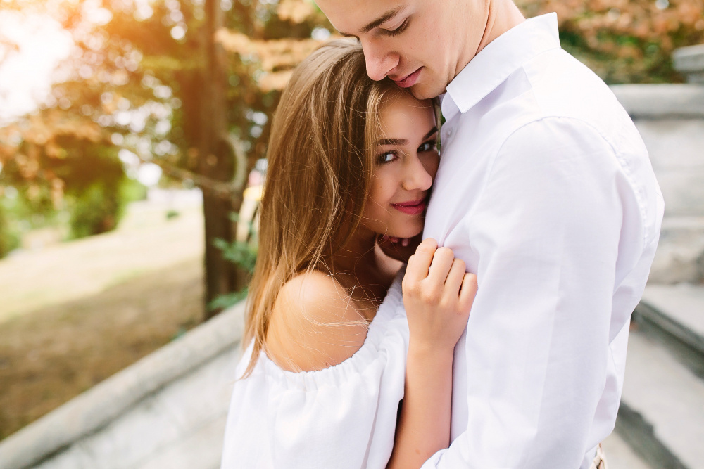 Девушка нежно обнимает парня, прижимаясь к нему и чувствуя заботу и близость в отношениях.