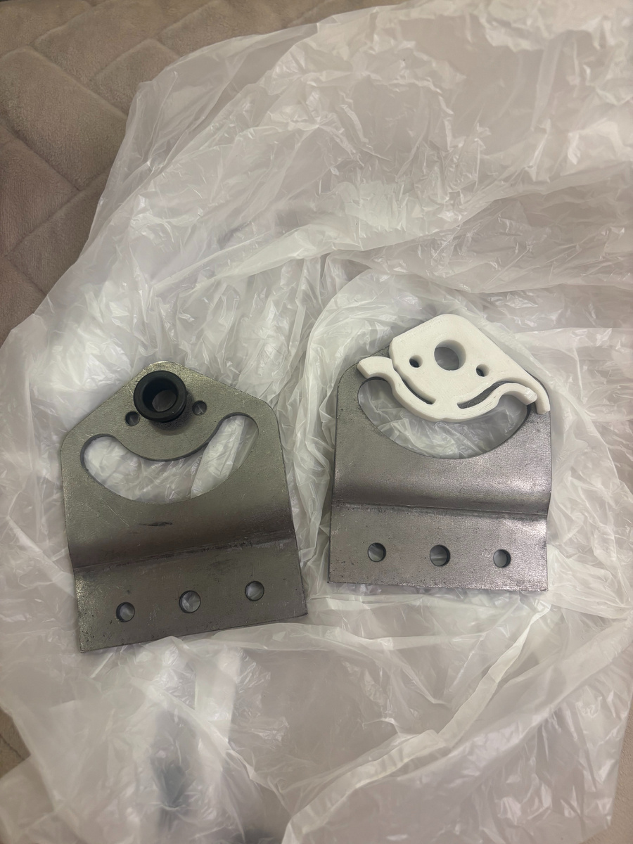 Металлические кронштейны под сварку к каркасу + белый фиксатор на правый кронштейн по ходу движения, который крепится на заклепки, черная втулка в левый кронштейн, колпачок фиксатора (нет на фото) на левый кронштейн