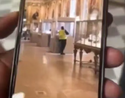 Мужчина в капюшоне и жёлтом жилете под видом рабочего вскрывает витрину в галерее Аполлона в Лувре