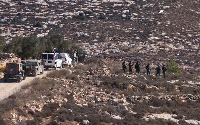 Израильские солдаты стоят на страже, пока палестинцы собирают оливки в деревне Турмус-Айя на Западном берегу реки Иордан, на окраине Рамаллы, 20 октября 2025 года. (Хазем Бадер / AFP).