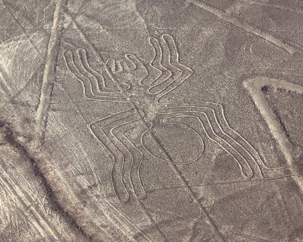 Аэрофотоснимок показывает геоглиф в виде паука, вычерченный длинными линиями на сухой равнине пустыни.