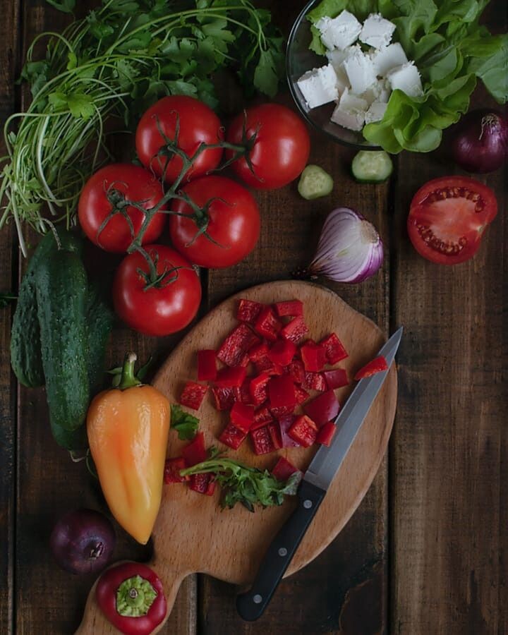 Нарезанные лук, перец и помидоры на разделочной доске