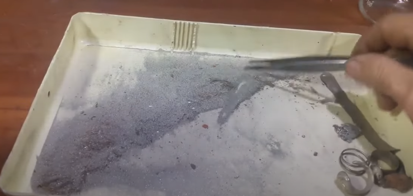 В процессе ювелирных работ неизбежно накапливаются отходы — серебряная пыль, грязь, остатки шлифовальных камней, песчинки от наждачки и даже недоделанные заготовки. Казалось бы, это просто мусор, но на самом деле в нём скрыто немало ценного серебра. Сегодня расскажу, как я переработал эти отходы и вернул их обратно в чистый металл.

Подготовка отходов

Со временем у меня собралась целая порция серебряной пыли с мелким мусором. В этом же наборе — несколько неудавшихся заготовок: недолитый перстень со знаком зодиака Козерог, пластина, кусочки от заготовок. Крупные детали я решил не растворять — они пойдут в следующее литьё. А вот пыль необходимо переработать, чтобы не потерять даже грамм драгоценного металла.

Для начала я взвесил всё содержимое — получилось **18,3 грамма** серебросодержащих отходов.

 Растворение серебра

Чтобы извлечь серебро, я использовал обычный электролит и немного воды. Для реакции добавил аммонийную селитру (аммоселитру) — это позволяет не расходовать азотную кислоту. Смесь перемешал и поставил на подогрев. Уже через пару минут началась активная реакция: всё закипело и зашипело. После нескольких минут кипячения раствор приобрёл зеленоватый оттенок, а на дне остался нерастворимый осадок — в основном песок и остатки шлифовальных материалов.

Проверка и фильтрация

После остывания я профильтровал раствор, а оставшийся осадок ещё раз прокипятил в азотной кислоте, чтобы убедиться, что всё серебро растворилось. Реакция была слабой — значит, почти весь металл уже в растворе.

Затем раствор разбавил водой и проверил кислотность — pH около 3, то есть кислый, как и нужно. Теперь настало время вытеснить серебро из раствора.

 Осаждение серебра на медь