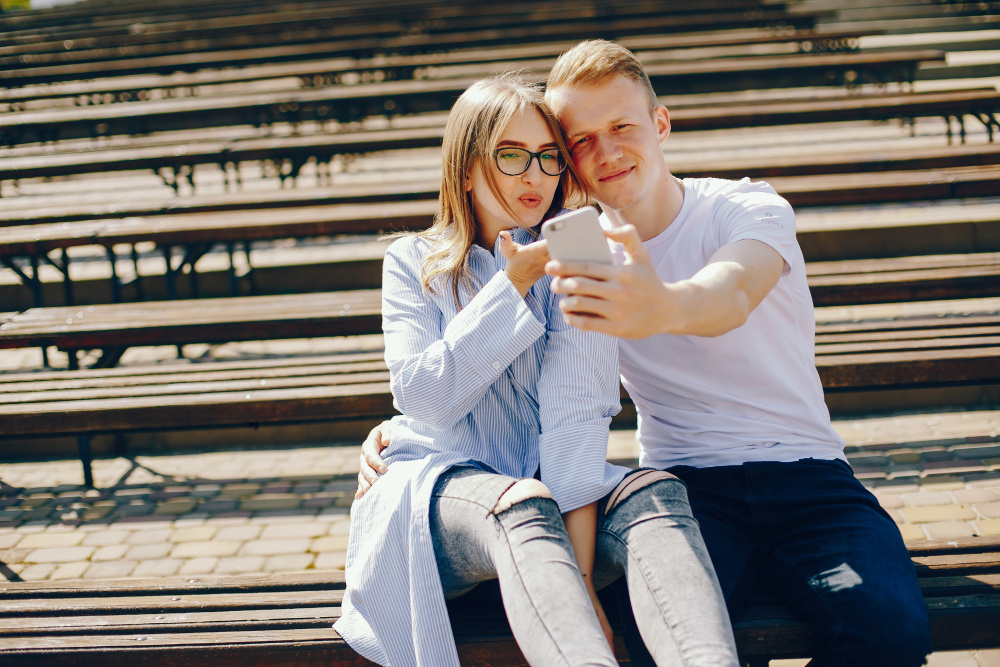 Пара улыбается и делает селфи, наслаждаясь временем вместе на улице — знакомство и любовь в реальной жизни без приложений.