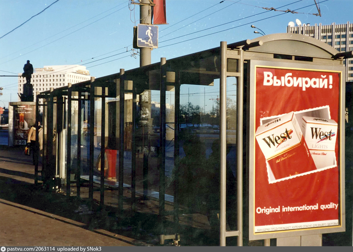 Реклама сигарет на остановке общественного транспорта около метро "Октябрьская". Предупреждающая надпись имеется, но заметить её, а тем более прочитать, очень сложно, 1995-1996. Автор фото: В.Т. Стигнеев. С сайта www.pastvu.com.
