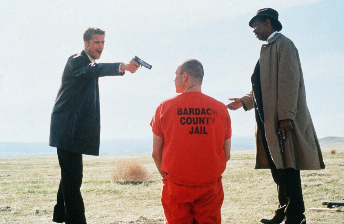 «Семь»: сцена в поле, детектив с пистолетом и заключенный в оранжевой робе, (источник: kinopoisk.ru)