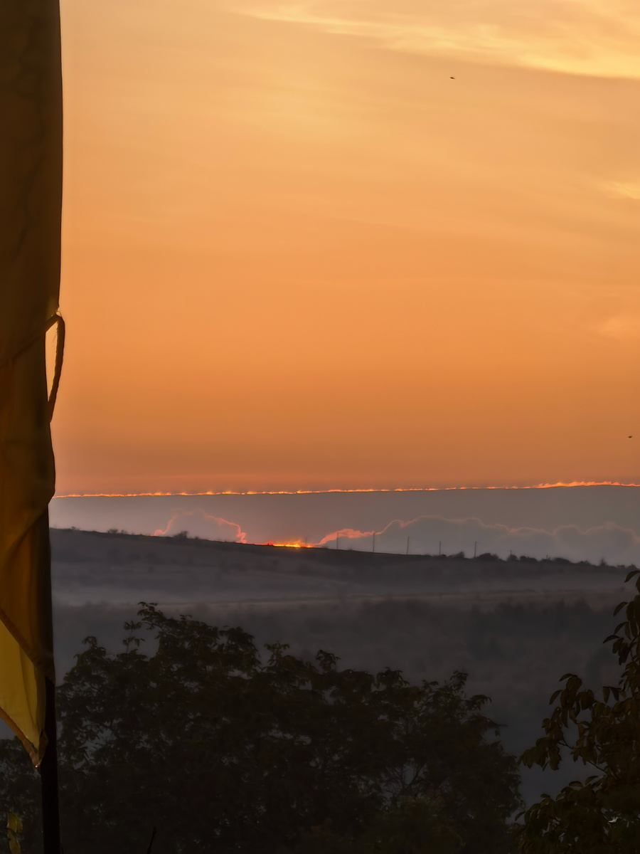 Солнце за холмом между двумя облаками