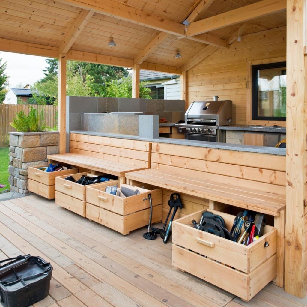 Практичный интерьер садовой беседки с встроенными скамьями-ящиками для хранения и безопасной зоной для мангала