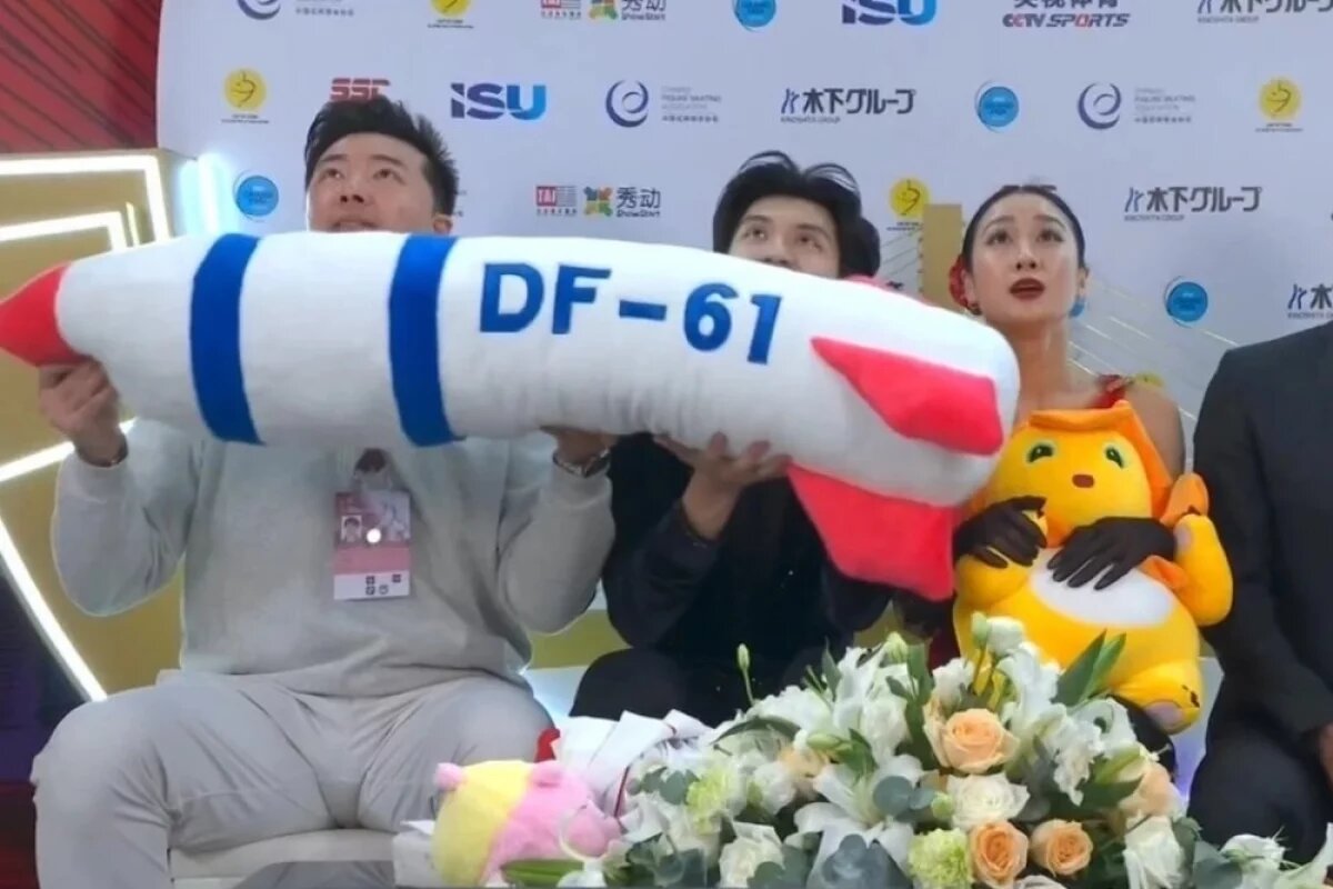    После выступления пары Жэнь Цзюньфэй / Син Цзянин на лед по традиции полетели мягкие игрушки, среди которых оказалась и плюшевая ракета с надписью DF-61.