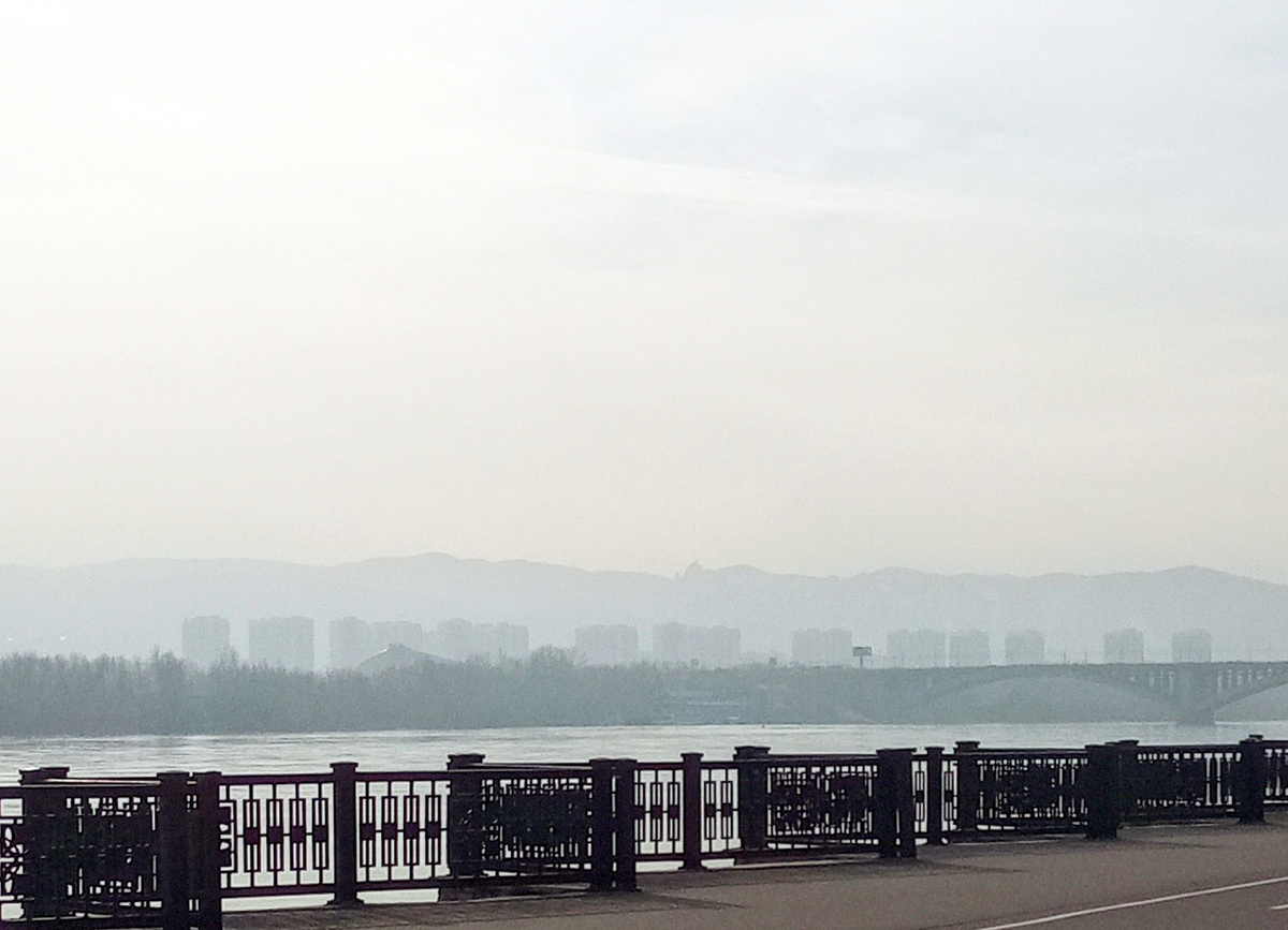 Очертания отрогов Саян слабо видны из-за дымки, окутавшей город. 