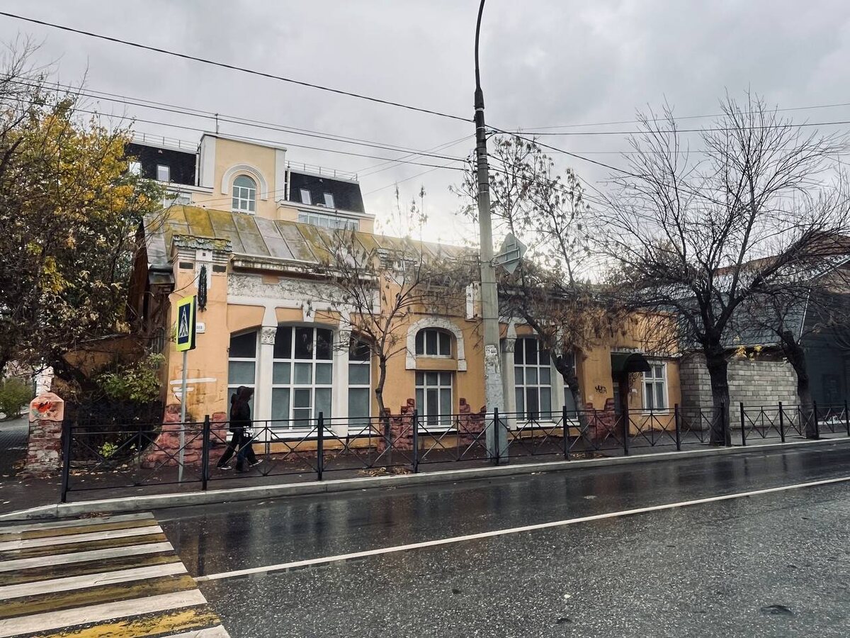 Главный фасад по Свердлова: крупные витрины и арочные проёмы; над крышей — поздние инородные надстройки.