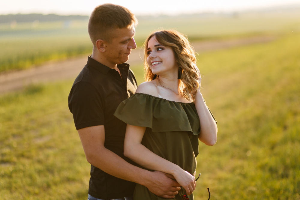 Молодая пара обнимается на закате, наслаждаясь тёплым вечером и романтической атмосферой свидания на природе.