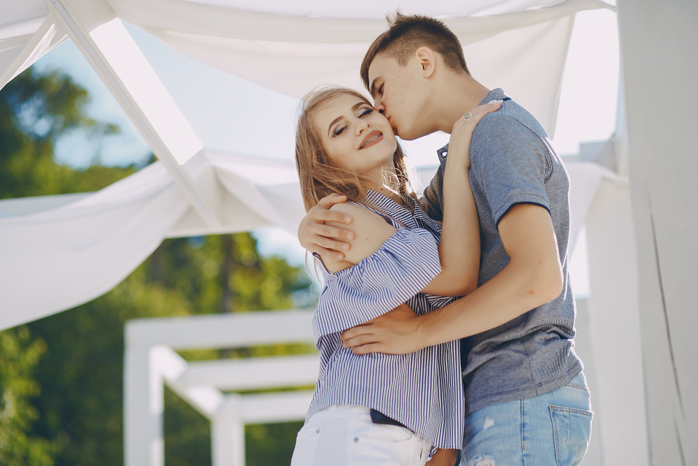 Молодая пара обнимается на фоне летней террасы — символ доверия, любви и взаимопонимания в отношениях