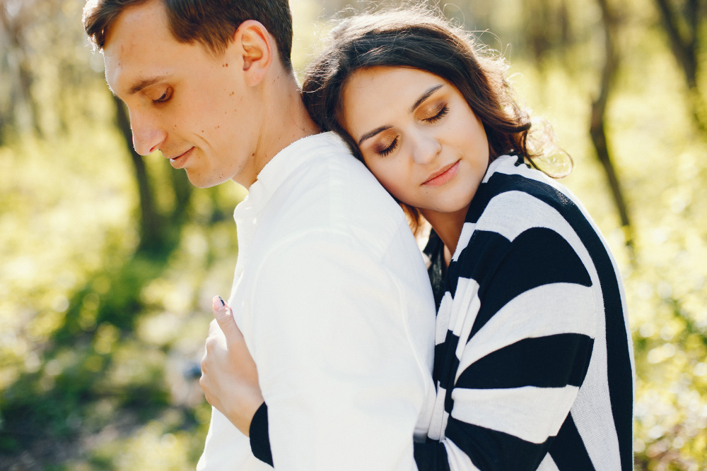 Женщина обнимает мужчину со спины в парке — момент нежности, понимания и поддержки в отношениях