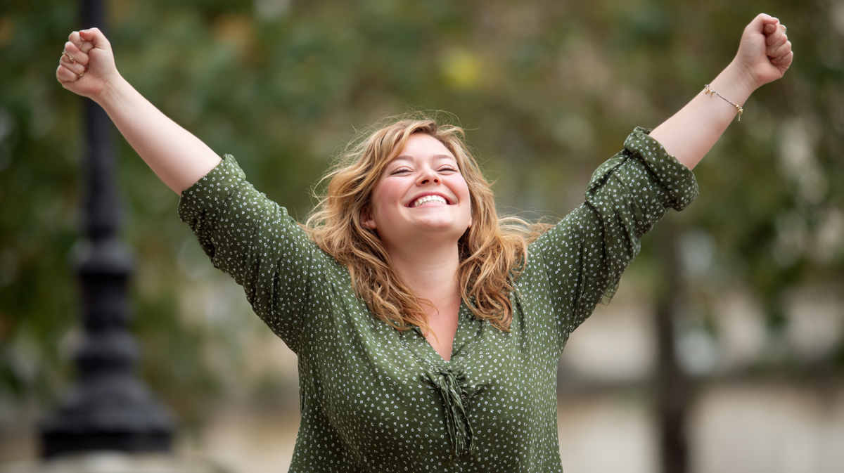 «Женщина радостно поднимает руки вверх после успешного завершения 7-дневного кето челленджа. Энергия, лёгкость и уверенность — результат участия в марафоне кето и следования календарю челленджа по кето-диете.»