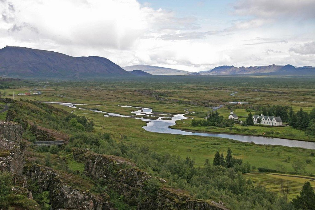 На берегу притаилась небольшая усадьба с белыми домами и церковью, окружённая темно-зелёными елями.