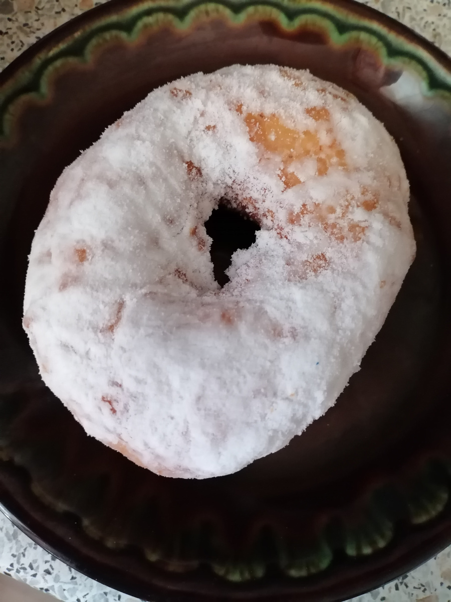 Пончик зажарен на масле, обильно посыпан сахарной пудрой, тесто дрожжевое сдобное, начинка отсутствует; вкус бесподобный – мягкий, воздушный; не смотря на всю, казалось бы, тяжесть структуры, в организме оседает пушинкой, а не кирпичом