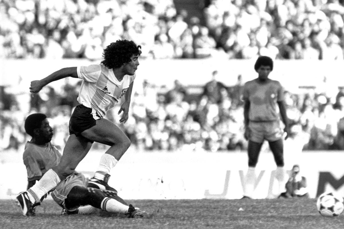 Аргентинский нападающий Диего Марадона (слева) во время матча между сборными Аргентины и Бразилии на стадионе «Сентенарио» в Монтевидео, Уругвай, 4 января 1981 года    📷