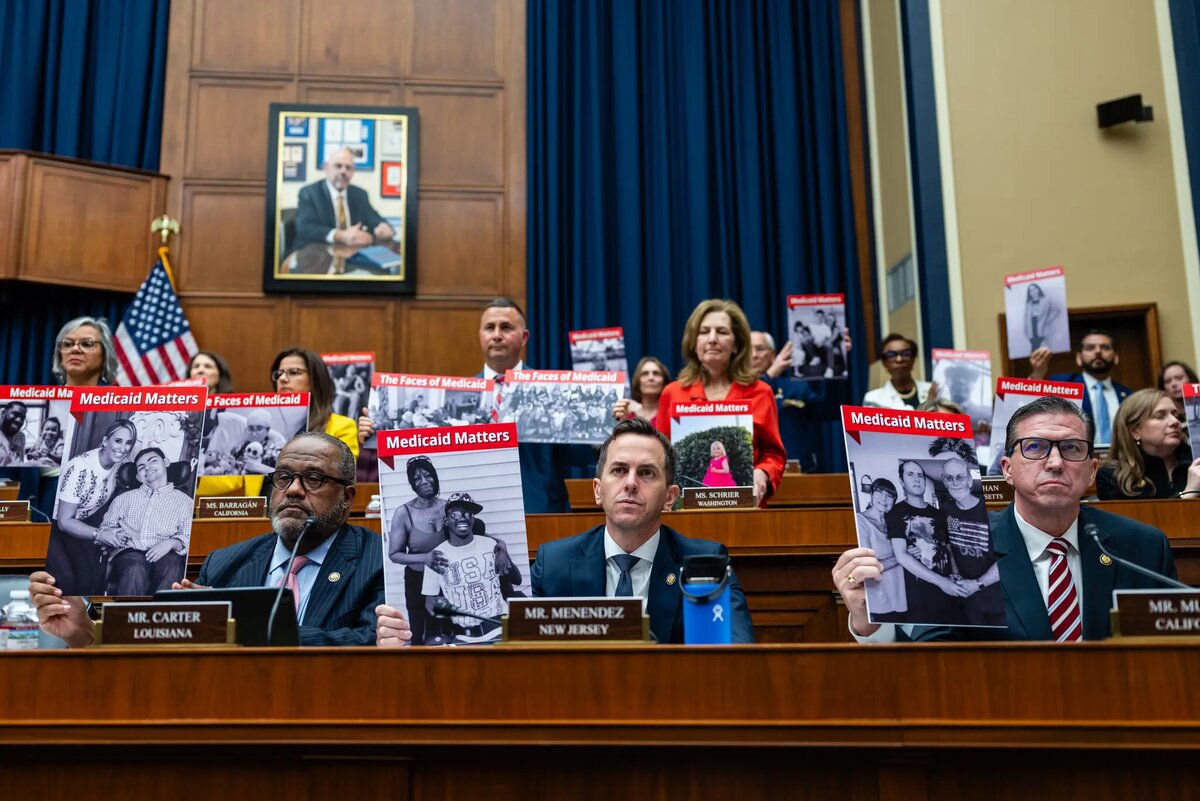 Демократы из Комитета по энергетике и торговле Палаты представителей США держат в руках постеры с фотографиями избирателей, которых они считают “лицами программы Medicaid”. ©Eric Lee/The New York Times