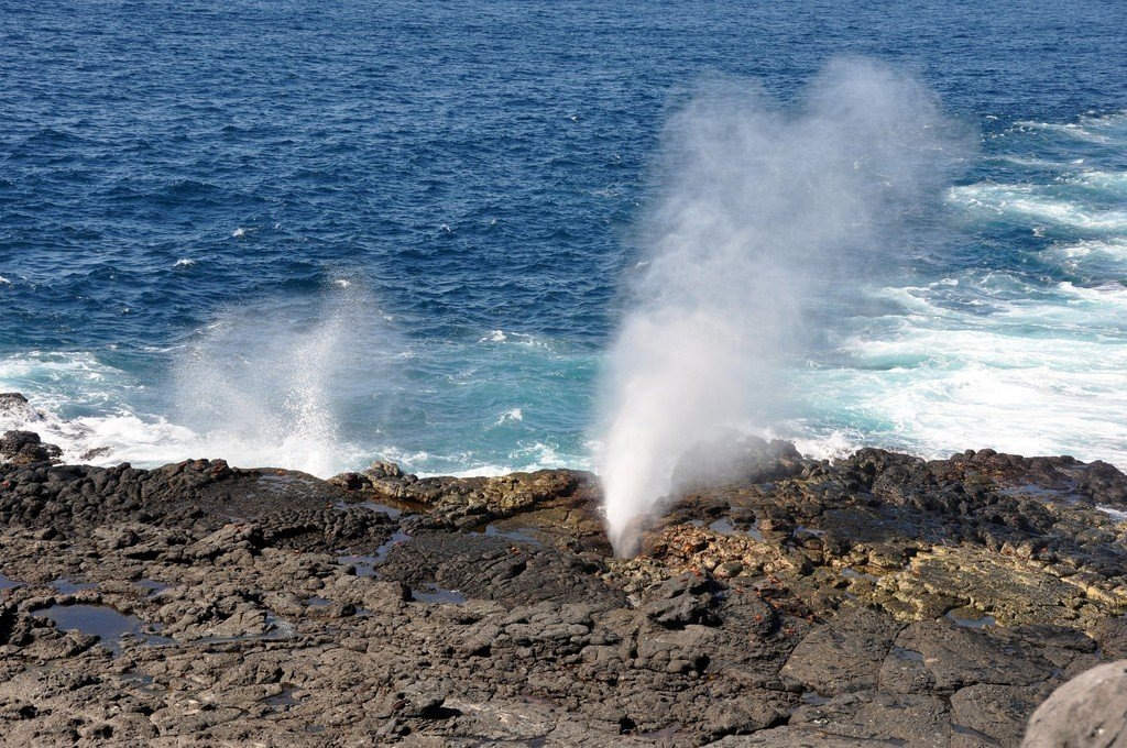 Бирюзовые волны разбиваются о берег, подчёркивая суровую вулканическую природу Галапагосов и их драматическое побережье.