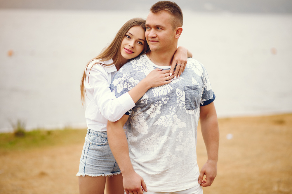 Молодая женщина обнимает мужчину сзади и улыбается — символ поддержки, заботы и доверия в отношениях.