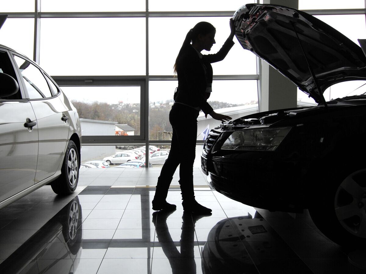    Посетительница осматривает автомобиль в автосалоне© РИА Новости / Михаил Мордасов