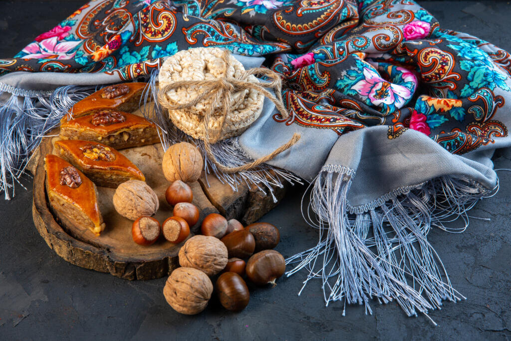    side view of baklava with whole nuts and rice breads on a shawl with tassel Журналист