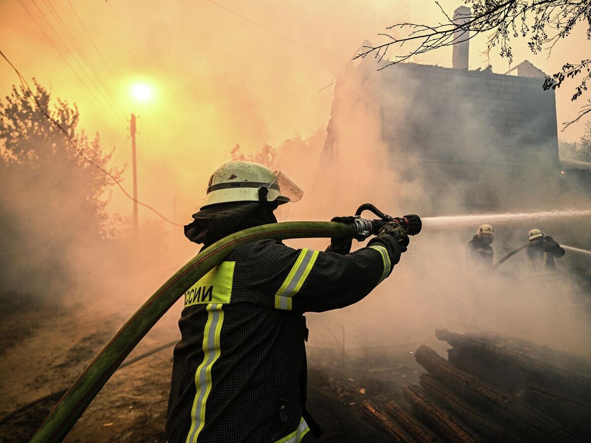    Сотрудники пожарной службы МЧС РФ тушат пожар в поселке Ольховские дачи Станично-Луганского округа Луганской народной республики© РИА Новости / Сергей Бобылев