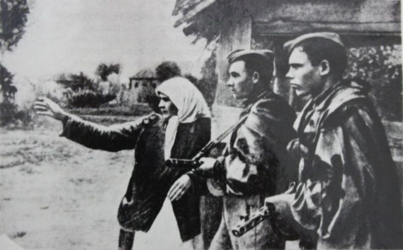 Жительница освобожденной советской деревни указывает разведчикам направление скрывшихся немецко-фашистских захватчиков