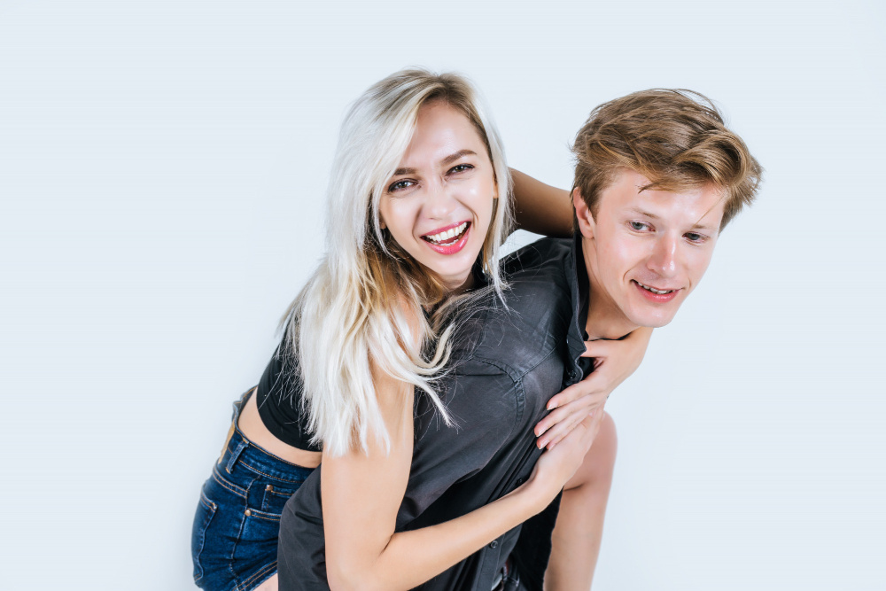 Молодая пара улыбается и весело обнимается, показывая доверие и лёгкость в отношениях.