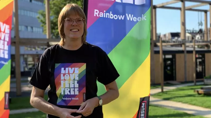 Улыбающийся человек в очках и футболке с надписью «live love feel free» на мероприятии в рамках Недели радуги.