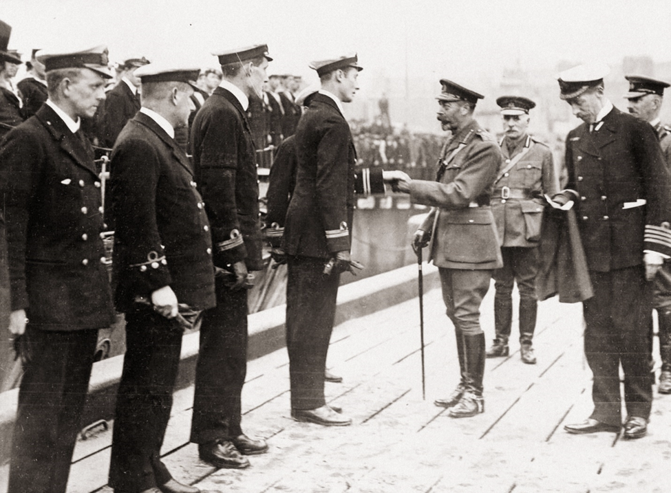 Король Георг V приветствует офицеров патрульного катера на судостроительной верфи D. W. Henderson & Co. в Глазго, 18 сентября 1917 года.