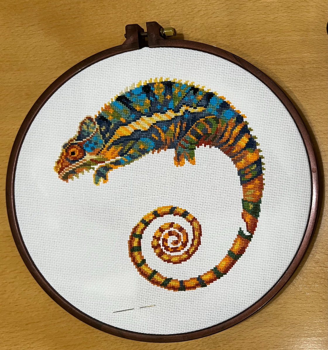 Хамелеон занимает почти треть площади. Но кажется, что меньше. Это он мимикрирует под белую канву