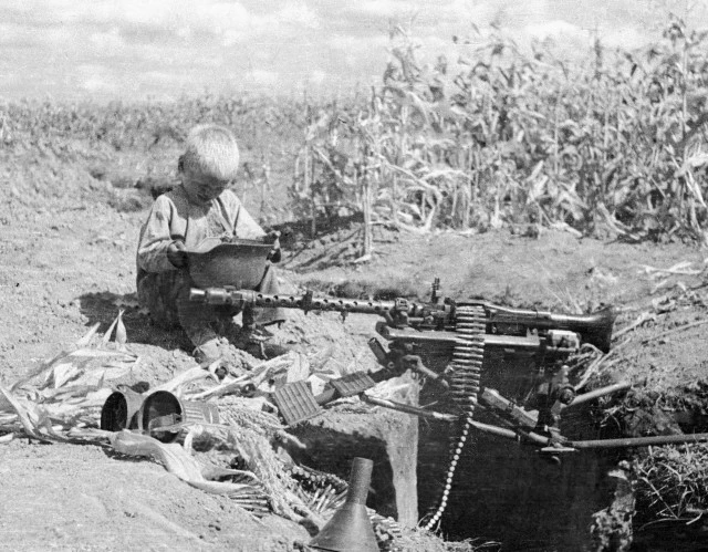 Мальчик рассматривает брошенное немецкое оружие. Украинская ССР, 1943 год. Фотограф: Георгий Липскеров