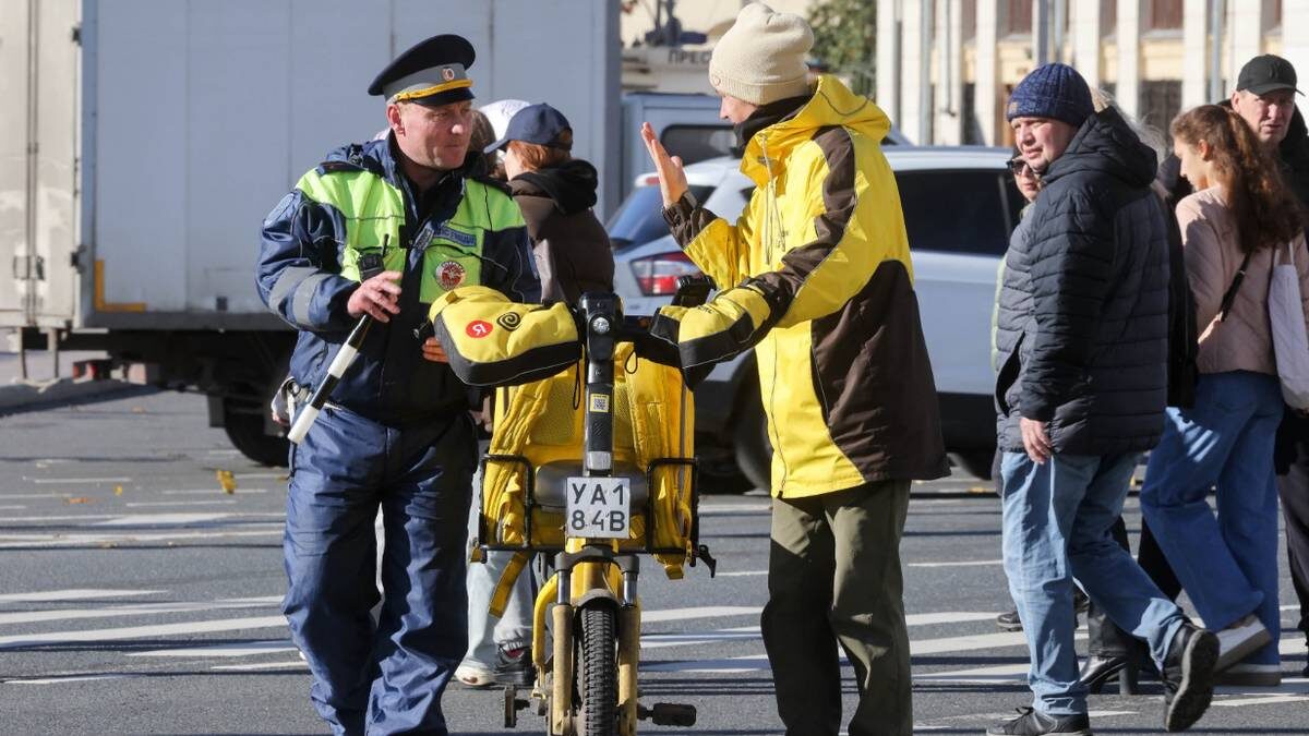    Инспектор ГИБДД и велокурьер во время профилактического рейда среди электросамокатчиков и велосипедистов / Фото: Сергей Карпухин / ТАСС