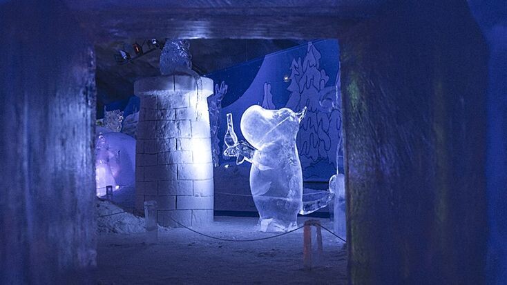 В ледяной пещере муми-троллей в Леппявирта завораживающе сияет скульптура персонажа, вырезанная изо льда, — её контуры мягко подсвечены холодным светом. 