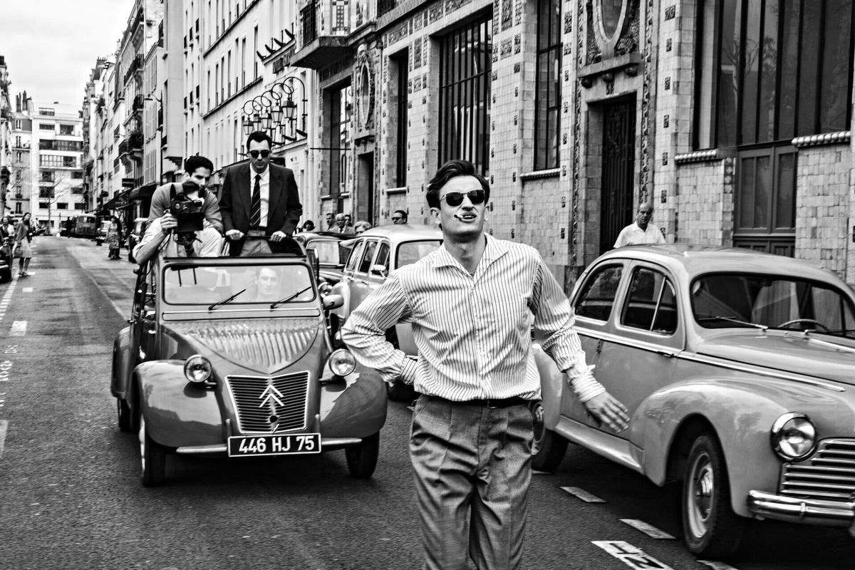 "Новая волна" (2025): черно-белый кадр со съёмок фильма на парижской улице с ретро-автомобилями, (источник: kinopoisk.ru)