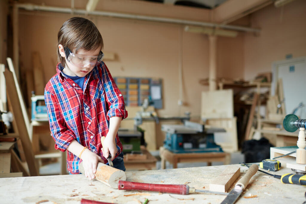    Boy with wood-chisel carving wooden plank Журналист